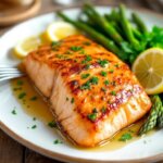 Garlic butter salmon fillet served with asparagus and lemon on a plate