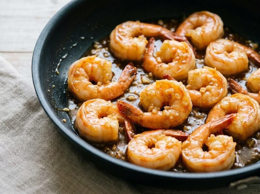 Shrimp tossed in glossy honey garlic sauce in a skillet